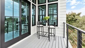 A balcony with two chairs and a table, large windows, and a railing. - Katydid Beach Bungalow by Avantstay Gulf Views New Construction in Seagrove (Santa Rosa Beach)