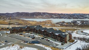 Un hôtel à plusieurs étages, doté d’une architecture moderne, situé près d’un plan d’eau et entouré de montagnes.