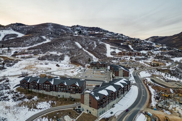 A large hotel with multiple buildings, a ski resort in the background, and a winding road.