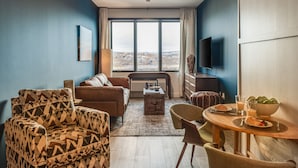 Un salon avec un canapé, un fauteuil et une table à manger où sont disposés des aliments pour le petit-déjeuner.