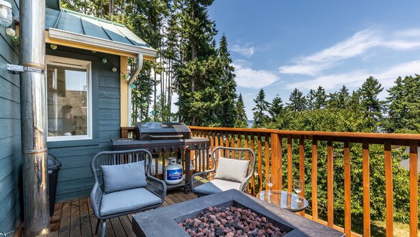 A deck with a fire pit, outdoor furniture, and a grill. - Seaside Getaway by Avantstay Deck w Views (Langley)