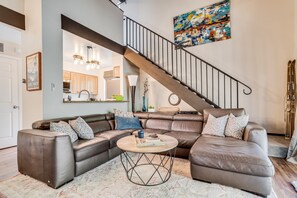 Ein modernes Wohnzimmer mit einer Eckcouch, einem runden Couchtisch und einer Treppe.