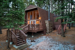 A cabin with a wooden deck and stairs leading to a large windowed porch. - Lundy Bearden Serene Tahoe Retreat With Deck Fireplace and Forest Views (Carnelian Bay)