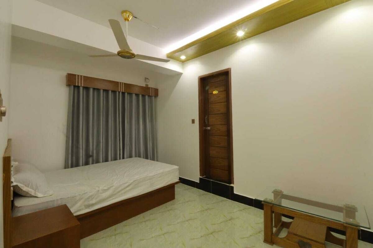 Une chambre à coucher avec un lit, un ventilateur de plafond, une porte en bois et une petite table.