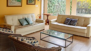 A living room with two sofas, a glass coffee table, wicker chairs, and framed artwork on the walls. - Alambari Village (Alambari)