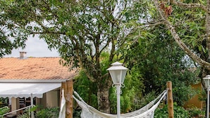 A garden with white wrought iron tables and chairs, a hammock, and a lamp post. - Alambari Village (Alambari)