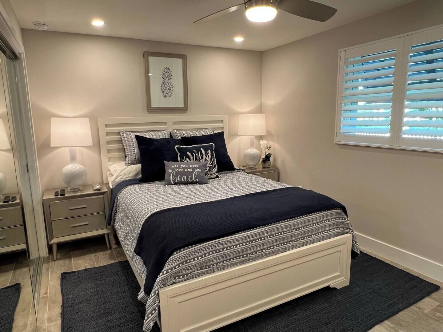 A neatly arranged bedroom with a bed, bedside tables, and a ceiling fan.