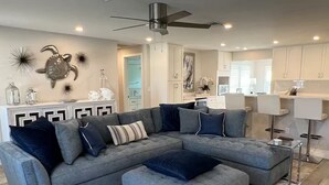A modern living room with a grey sectional sofa, a matching ottoman, and decorative wall art.