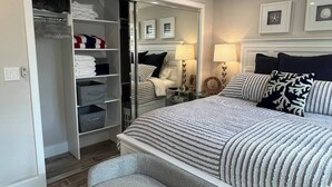 A bedroom with a bed, bedside tables, a wardrobe, and a mirror.