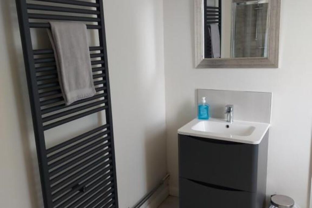A bathroom with a towel rack, a sink, and a mirror.