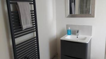 A bathroom with a towel rack, a sink, and a mirror.