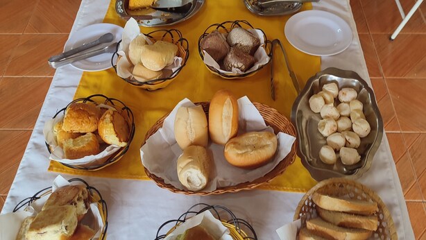 A buffet table with various food items including bread, pastries, and fruits. - Pousada Santo Antônio (Santo Antonio do Pinhal)