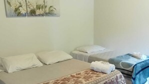 A bedroom with a large bed, two smaller beds, a painting on the wall, and a patterned floor. - Pousada Santo Antônio (Santo Antonio do Pinhal)