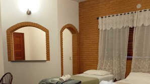 A room with two beds, a wooden chair, a table, and a mirror. - Pousada Santo Antônio (Santo Antonio do Pinhal)