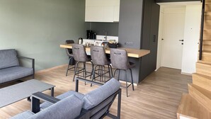 Ein modernes, kompaktes Wohnzimmer mit Essbereich, Küchenzeile und Treppe.