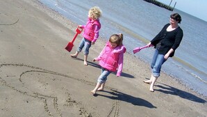 Ein sandiger Strand mit Fußabdrücken und einem Herz, das in den Sand gezeichnet wurde.