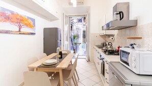 A modern kitchen with a dining area, a microwave, a gas stove, and a refrigerator. - Elegantis Giolitti Suite Apartment with Private Balcony (Roma)