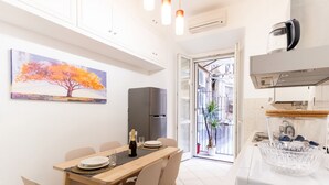 A modern kitchen with a dining area, a refrigerator, and a view through an open door. - Elegantis Giolitti Suite Apartment with Private Balcony (Roma)