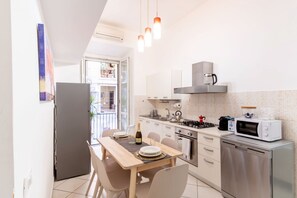 Een moderne keuken met een eettafel, stoelen, een koelkast, een fornuis, een magnetron en een koffiezetapparaat.