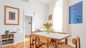 A dining area with a white table, wooden chairs, a vase with flowers, and artwork on the walls. - Elegantis.it Des Artistes Apartment (Roma)
