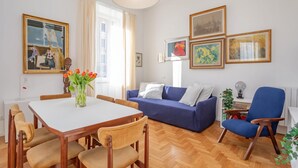 A modern living room with a dining table, blue sofa, and a blue armchair. - Elegantis.it Des Artistes Apartment (Roma)