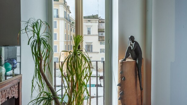 A room with a view of buildings through a window, a potted plant, and a statue on a wooden stool. - Elegantis Dimora dell'Architetto in Campo de' Fiori With private terrace (Roma)