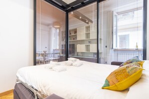 Un hotel moderno con una cama grande, un separador de vidrio y vistas a la ciudad.