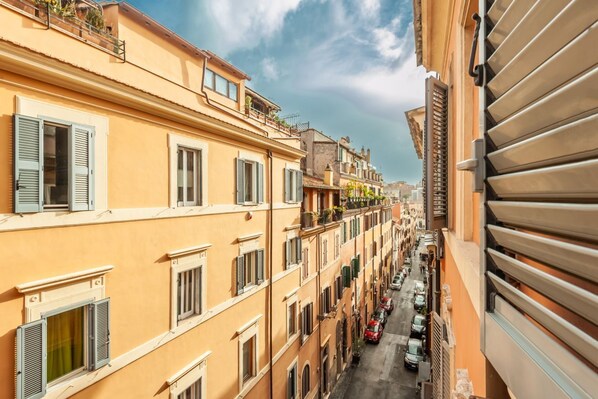 A narrow street lined with multi-story buildings, featuring balconies and shutters.
