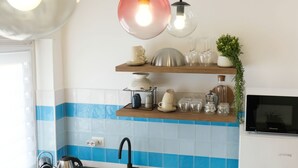 A kitchen with a sink, a kettle, a microwave, and a shelf with glassware and a plant. - Elegantis Santa Croce Suite Apartment (Roma)