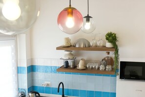 A kitchen with a sink, a kettle, a microwave, and a shelf with glassware and a plant. - Elegantis.it Santa Croce Suite Apartment (Roma)