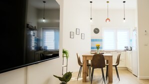 A modern kitchen with a dining area, a large flat-screen TV, and pendant lighting. - Elegantis Santa Croce Suite Apartment (Roma)
