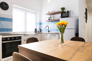 A modern kitchen with white cabinets, a wooden table, and a vase of yellow tulips. - Elegantis.it Santa Croce Suite Apartment (Roma)