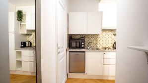 A compact kitchen with white cabinets, a microwave, a dishwasher, and a coffee maker.