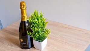A bottle of wine and a potted plant on a wooden table.