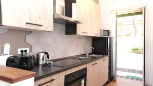 A compact kitchen with wooden cabinets, a microwave, a kettle, and a toaster.