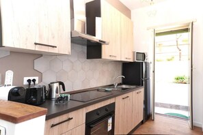 A compact kitchen with wooden cabinets, a microwave, a kettle, and a toaster.