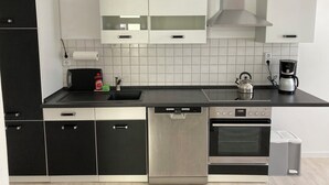 Een moderne keuken met roestvrijstalen apparatuur, waaronder een vaatwasser, oven en koffiezetapparaat.