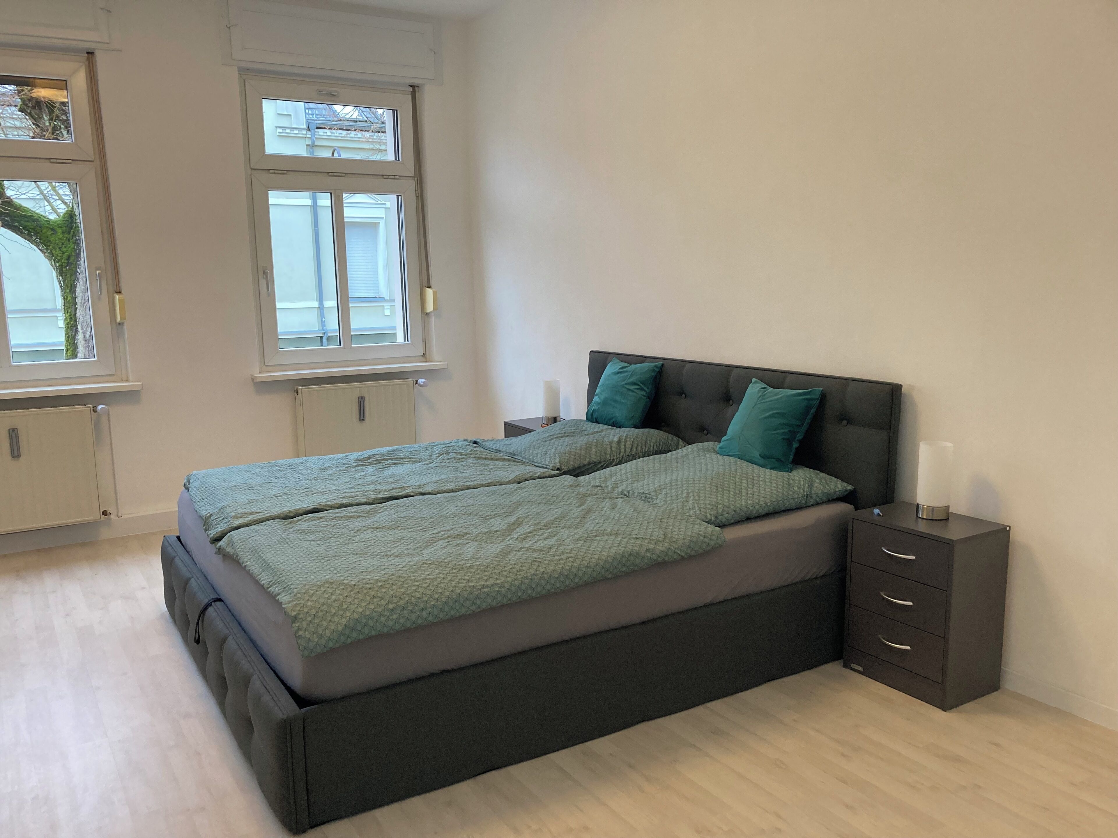 Une chambre avec un grand lit, deux tables de chevet et une fenêtre.