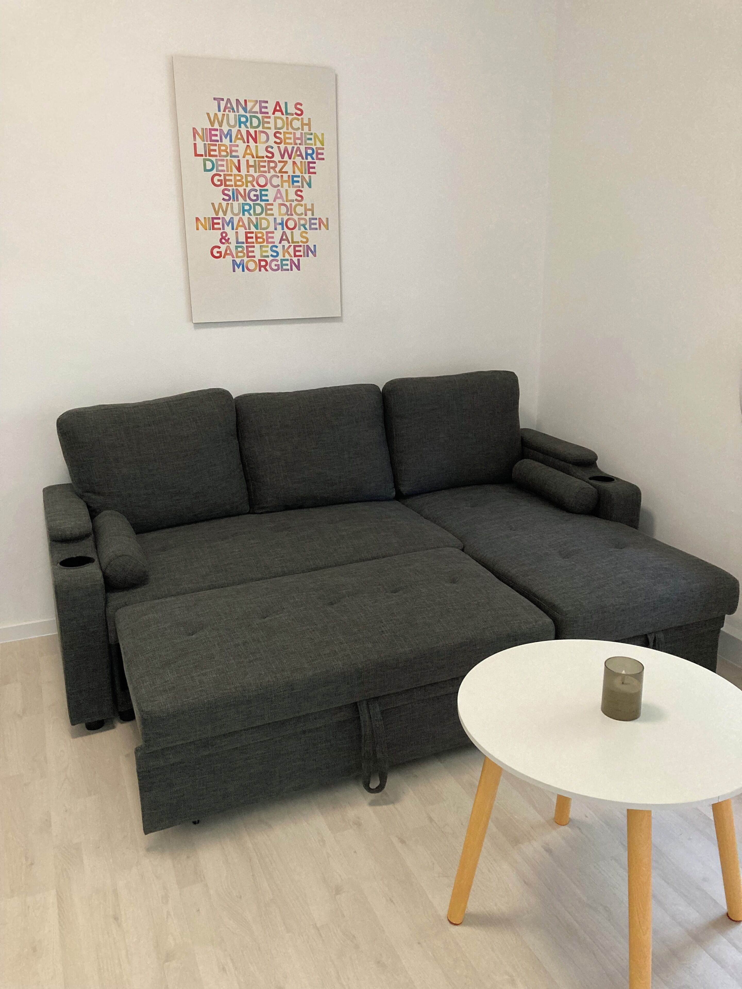 Un canapé d’angle gris avec une table basse blanche devant.