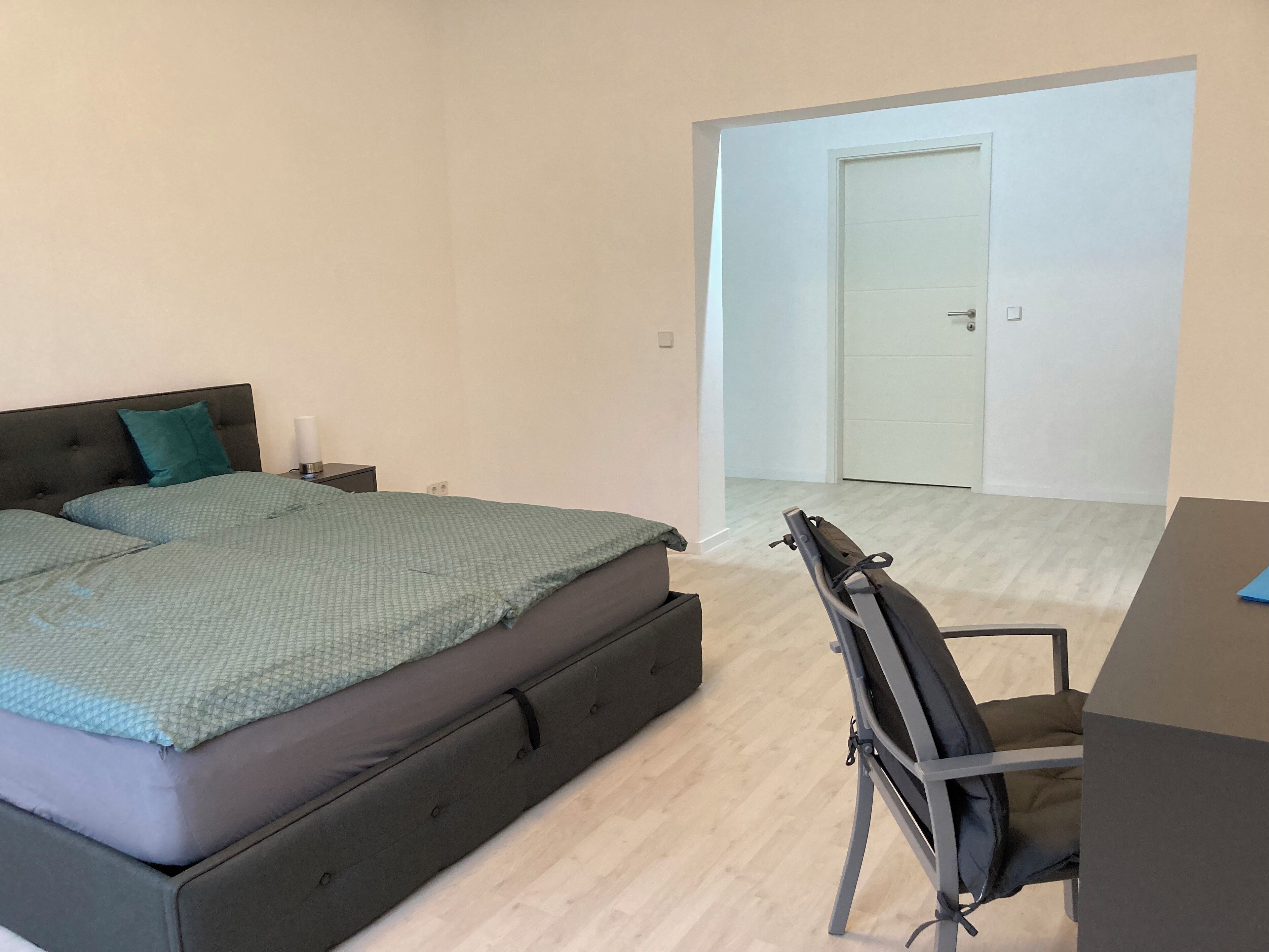A bedroom with a bed, a desk, and a chair.