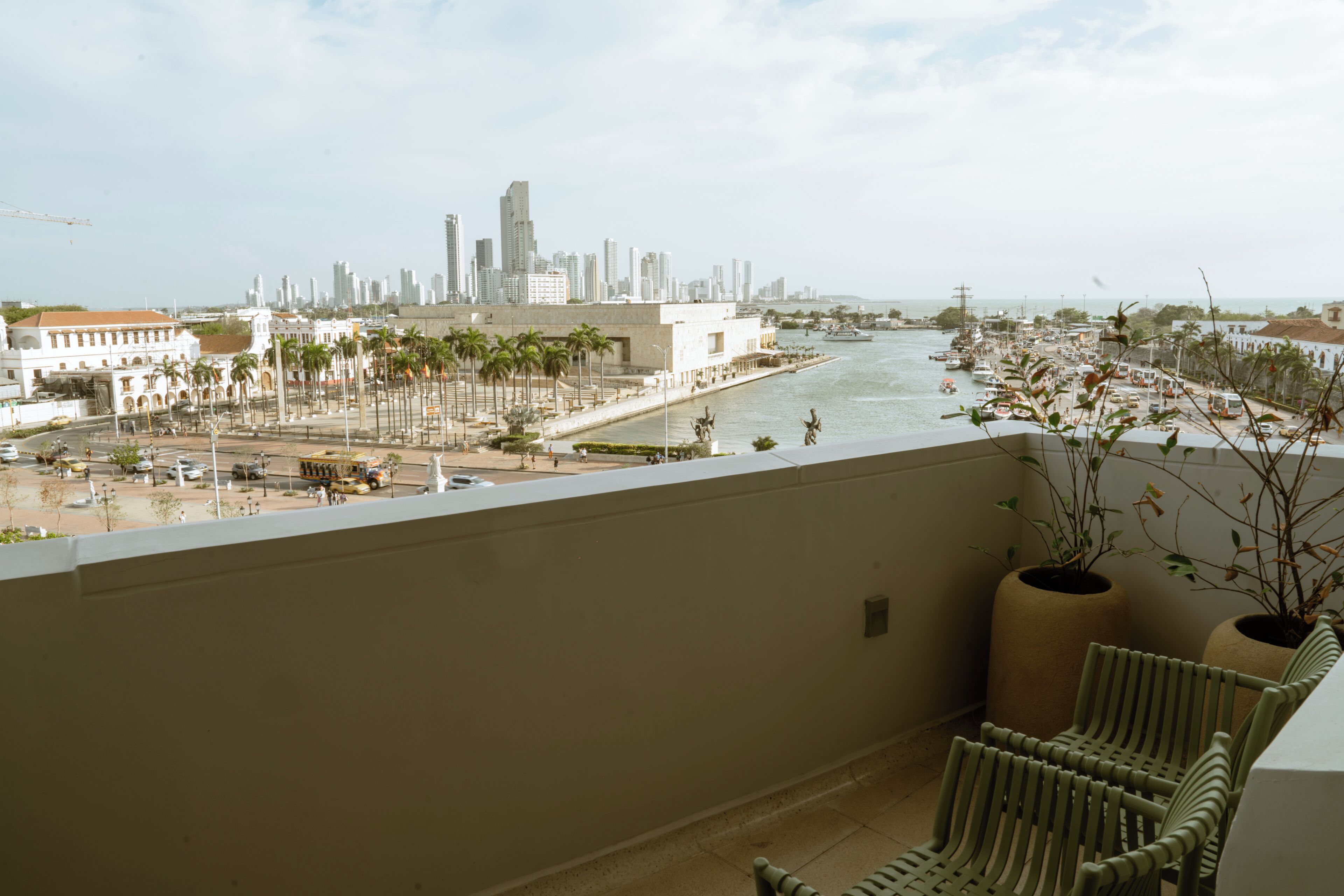 Een balkon met uitzicht op een stadsbeeld, palmbomen en een rivier.