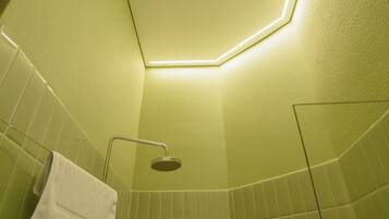 A bathroom with a shower, a towel rack, and a ceiling light fixture.