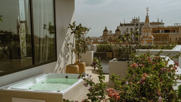 Eine Dachterrasse mit Whirlpool, Blumentöpfen und Blick auf historische Gebäude.