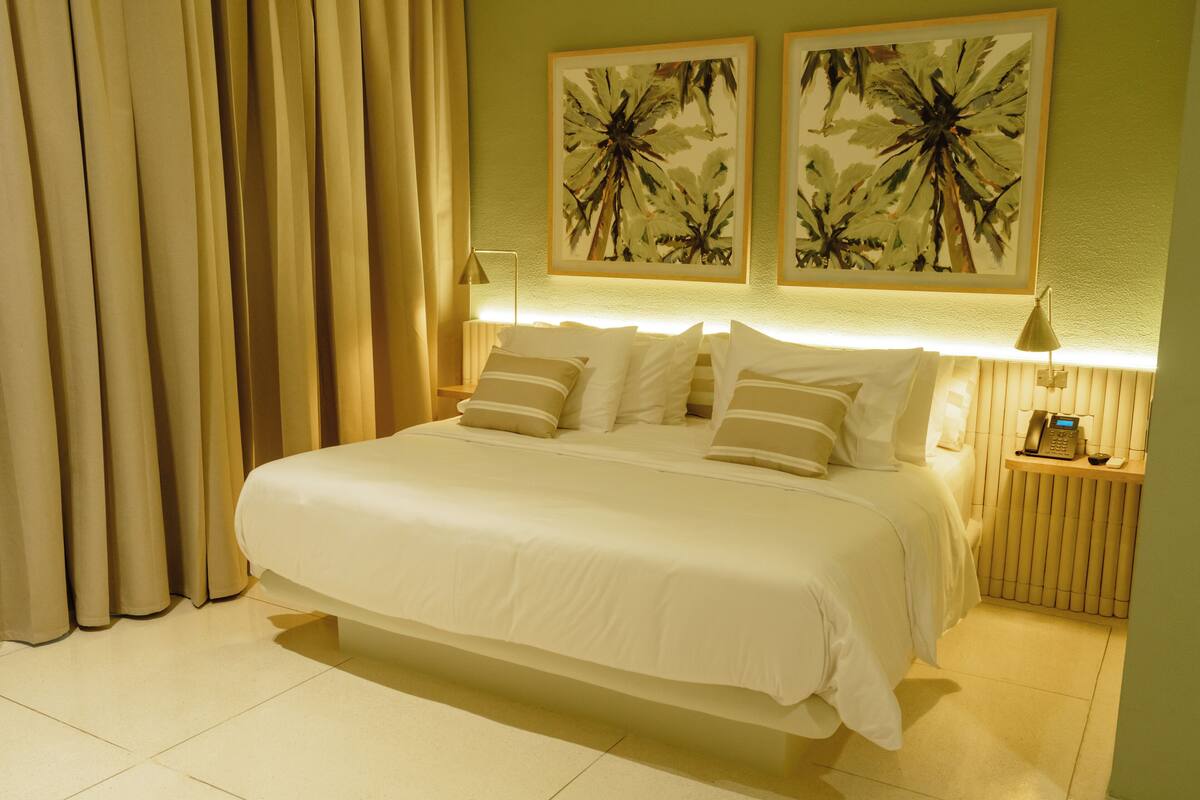 A hotel room with a large bed, two wall-mounted lamps, and a telephone on a bedside table.