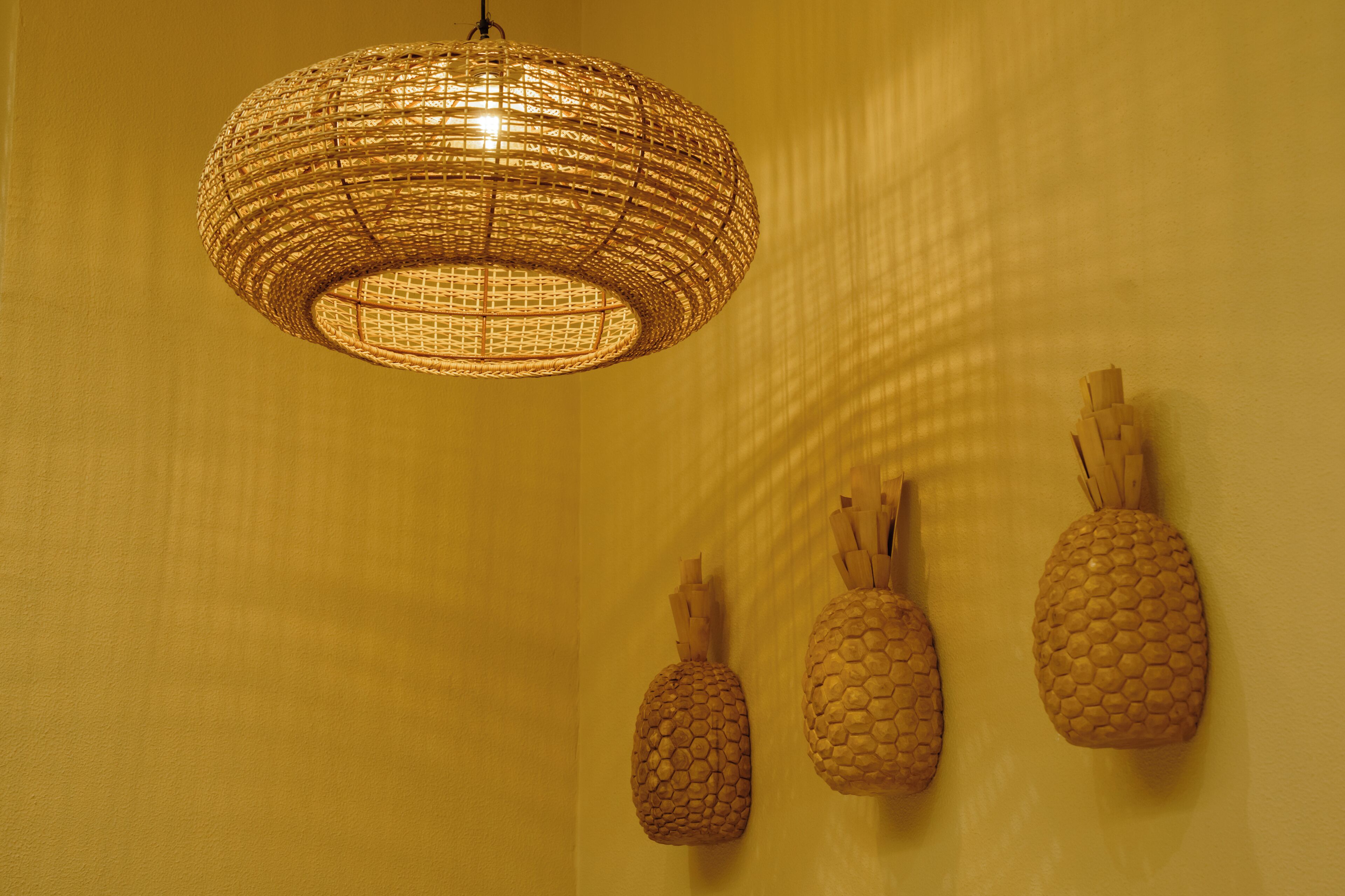 Una lámpara de techo tejida y tres adornos de pared con forma de piña.