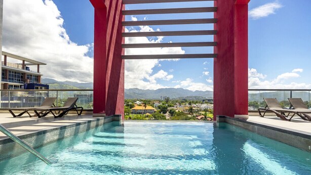 A pool with a view of mountains, red pillars, and lounge chairs.