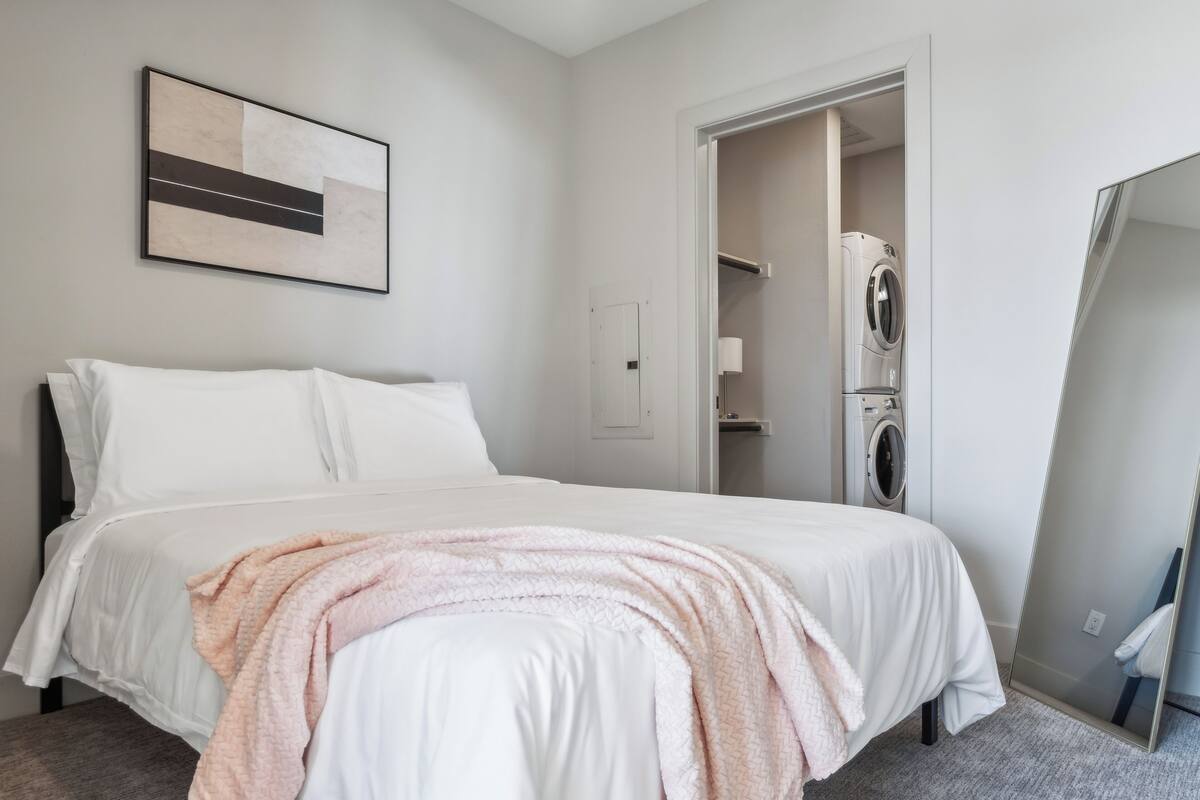 Une chambre moderne équipée d’un lit, d’une machine à laver et d’un miroir.