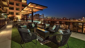 Un patio al aire libre con asientos, una chimenea y vistas a la ciudad al anochecer.
