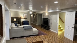 Een woonkamer met een bank, televisie en een eethoek met een tafel en stoelen.
