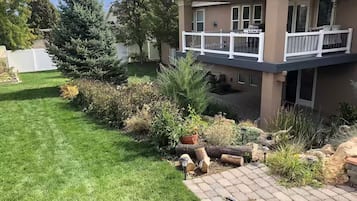 A two-story house with a balcony, a well-maintained lawn, and various plants and shrubs.